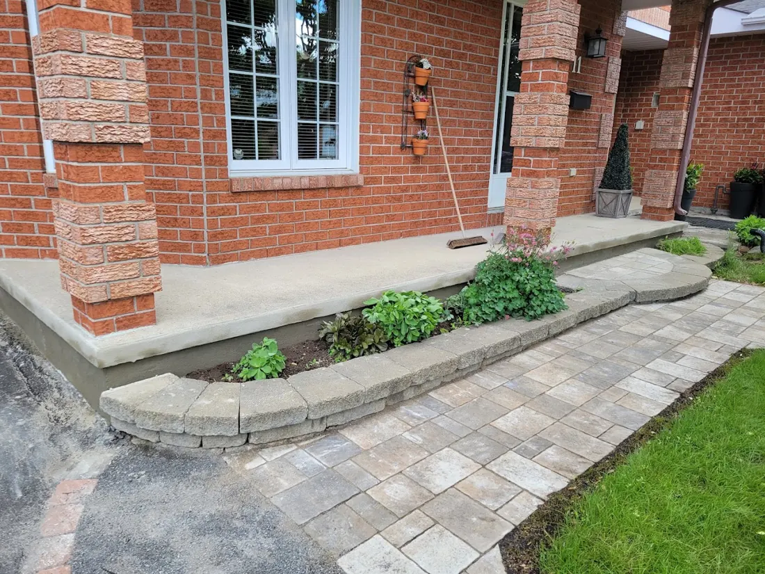 Red brick home with a new interlock walkway and low stone wall